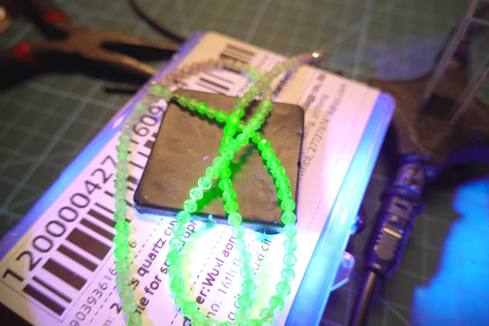 Green fluorescent bead necklace under UV — vivid green emission from the plastic