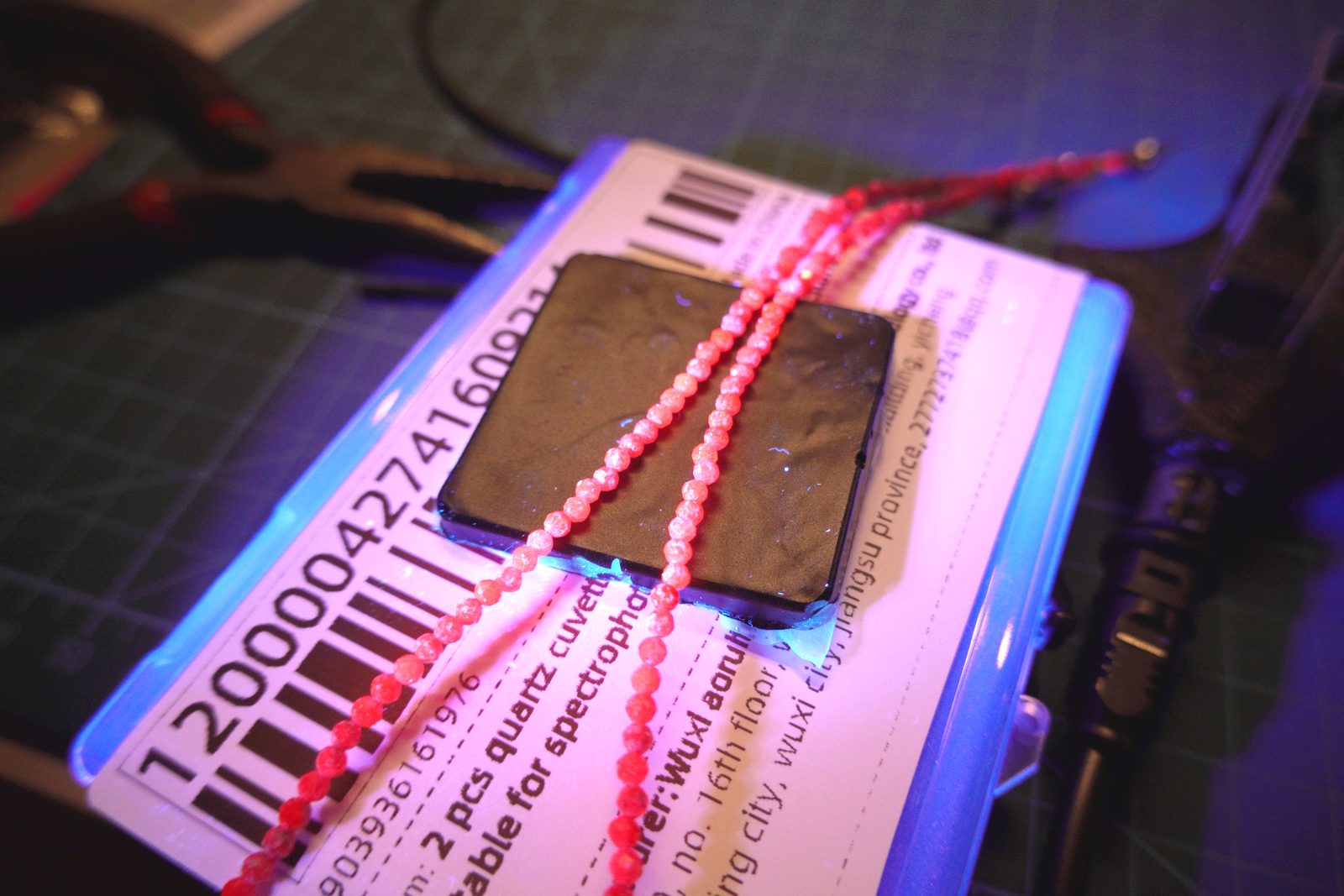 Red bead necklace under UV — warm orange-red fluorescence
