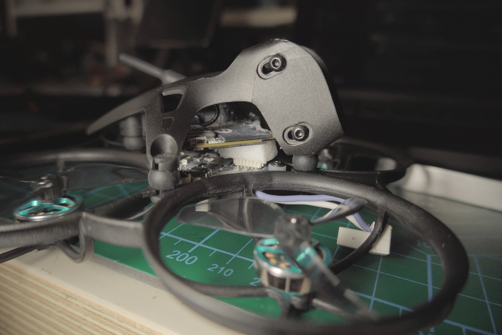 Side view of the Meteor75 Pro II on a cutting mat, showing a small pale foam block glued under the canopy near the connector
