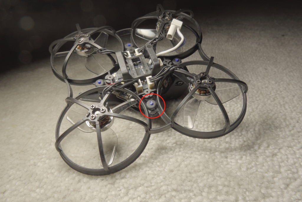 Meteor75 Pro II from the rear three-quarter, with a red circle marking one of the flight controller gummy grommets that has TPU filament inserted